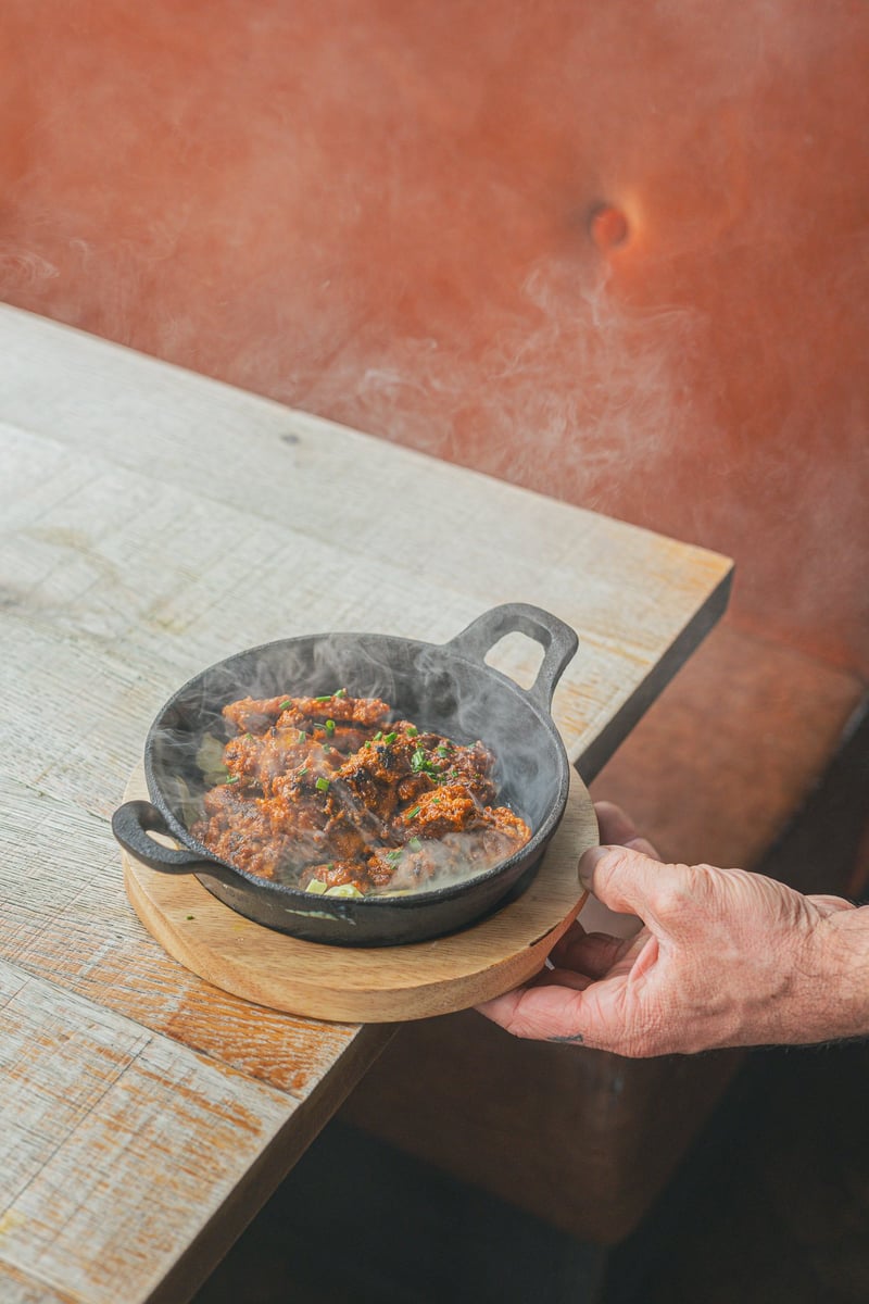 A server setting a sizzling skillet down at a table