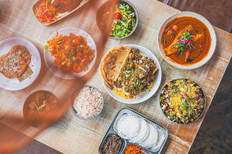 A table of Sri Lankan dishes seen from above, with curries, string hoppers, sambols, parotta and rice